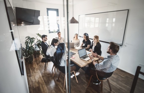 A stock photo of office workers sitting at a table for a meeting