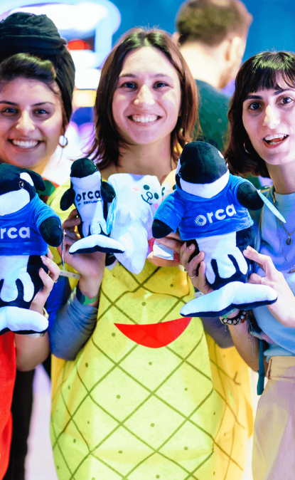 A photo of Orca colleagues holding the Orkie stuffed animal