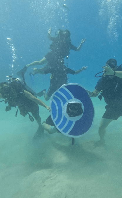 A photos of Orca colleagues suba diving with the Orca "O" sign